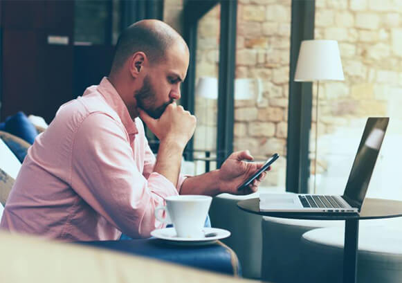 A guy looking at his phone in a coffee shop 