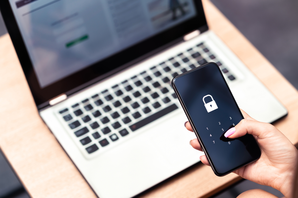 laptop and a mobile in a hand with a security icon